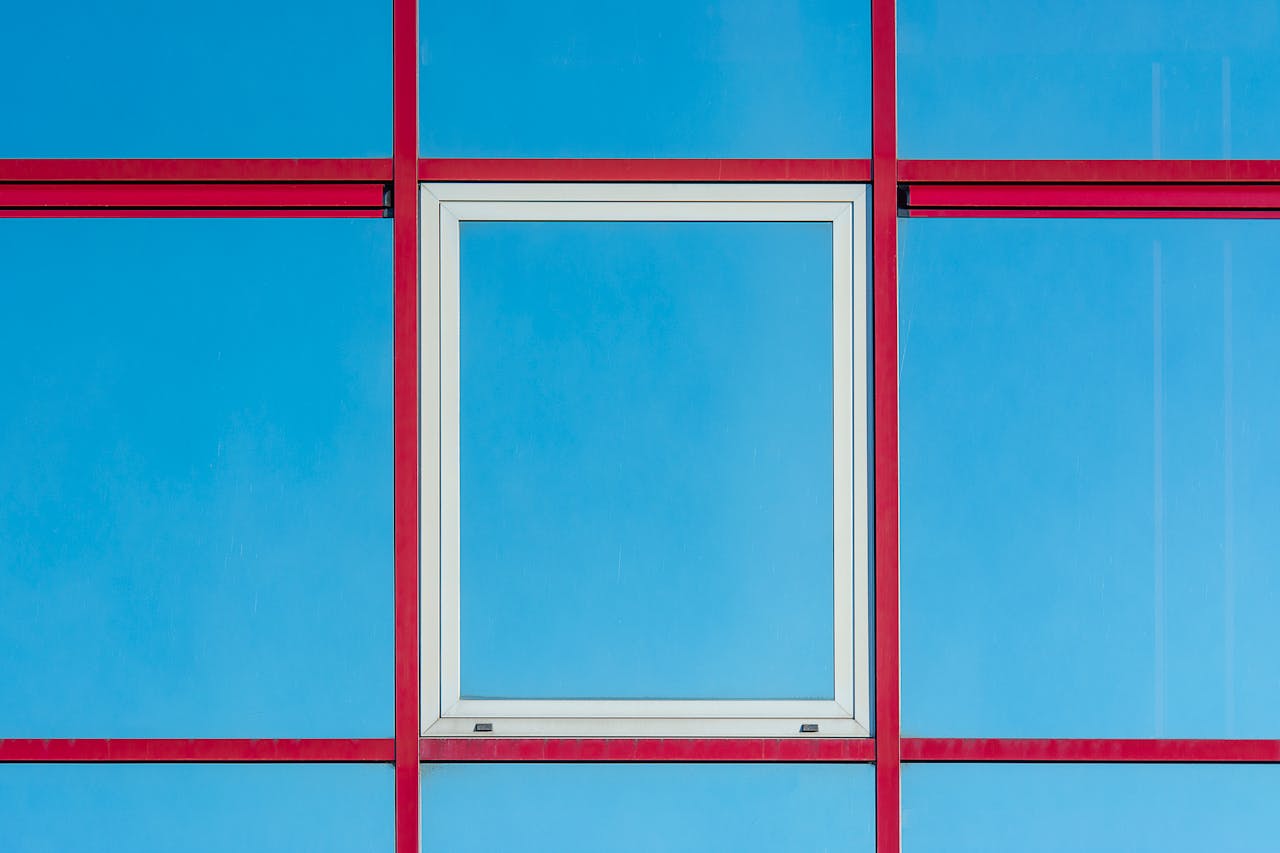 Modern architectural facade with red frames and blue glass panels.